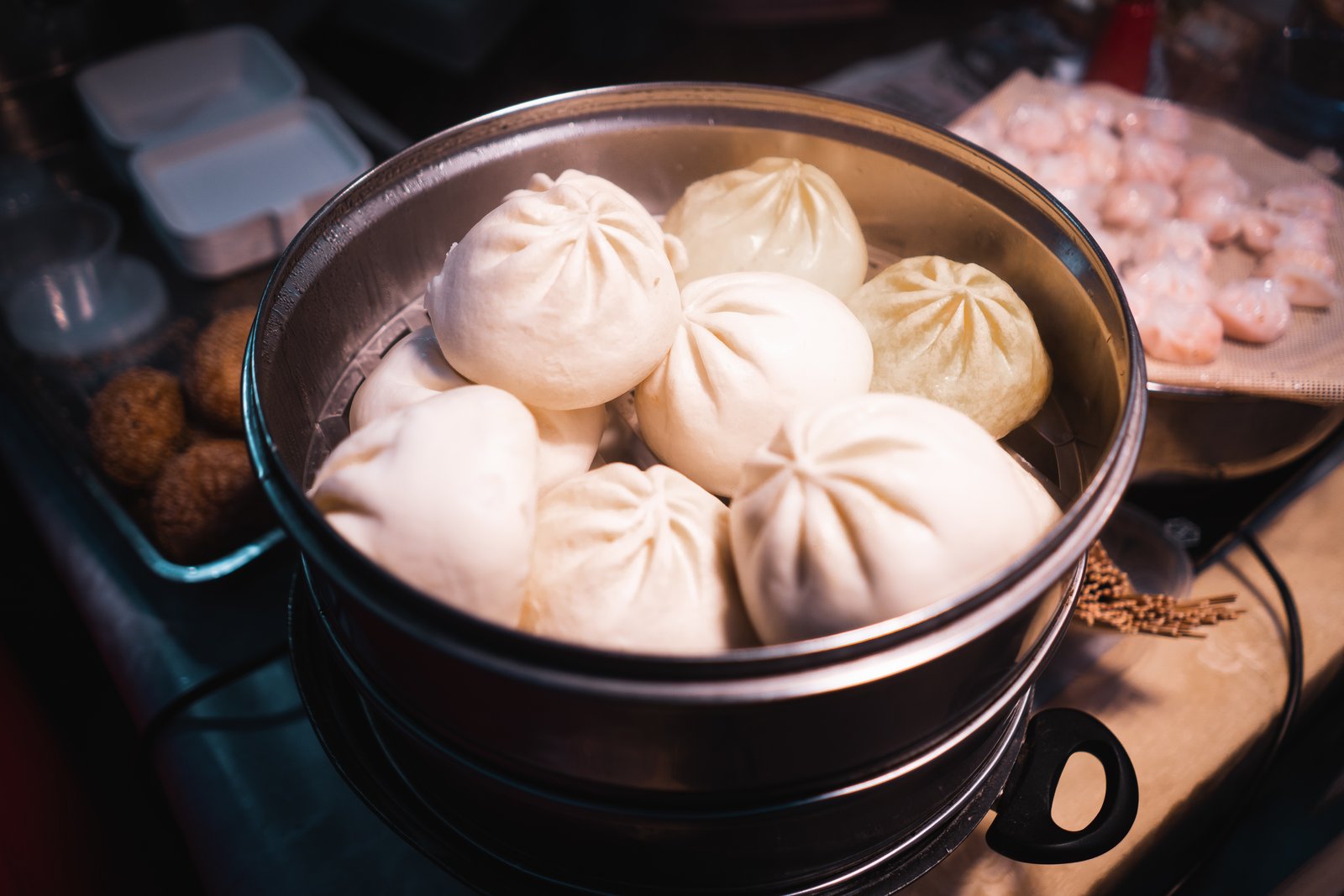Steamed baozi with pleated tops in a metal steamer basket