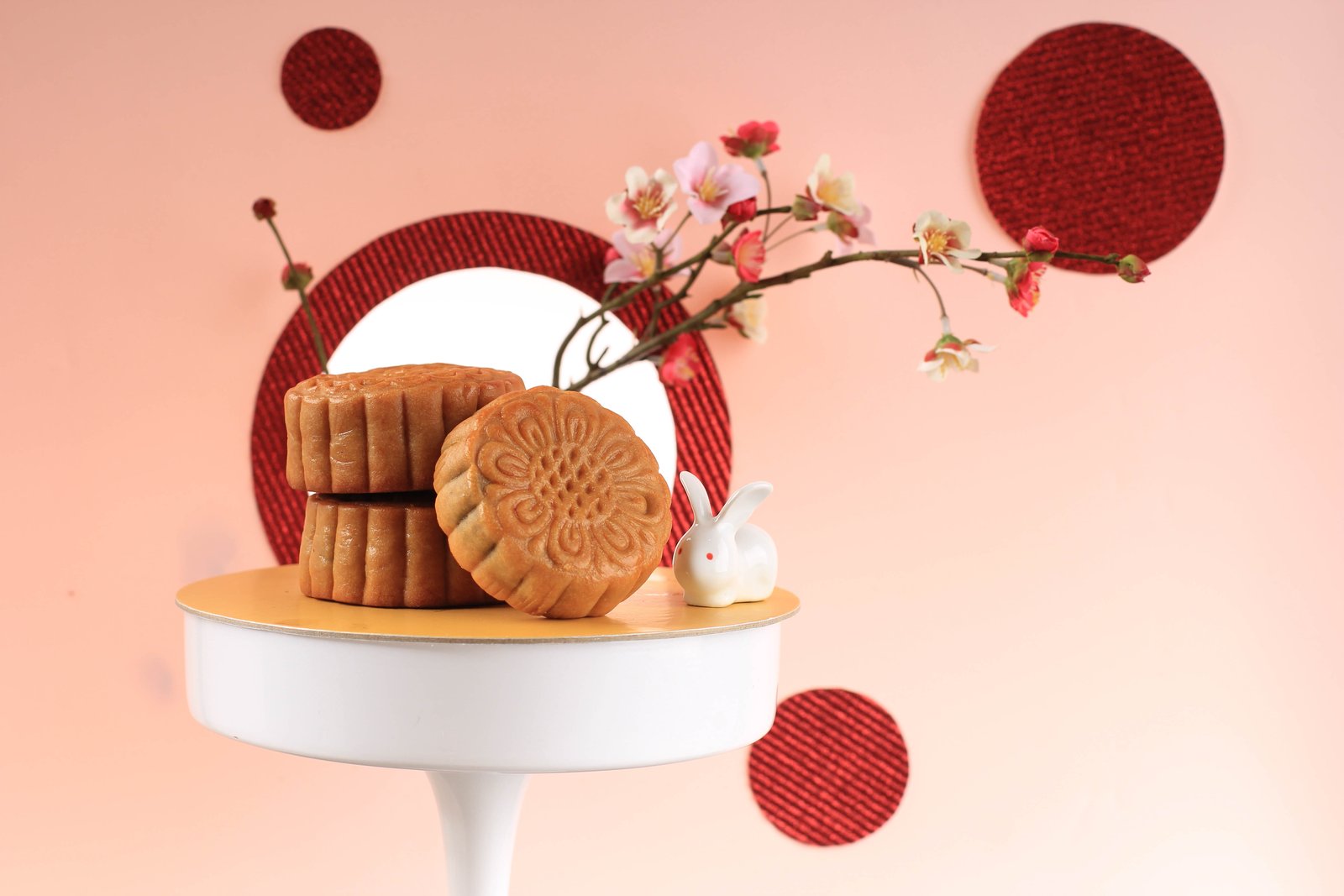 Stamped mooncakes stacked beside a sprig of blossom