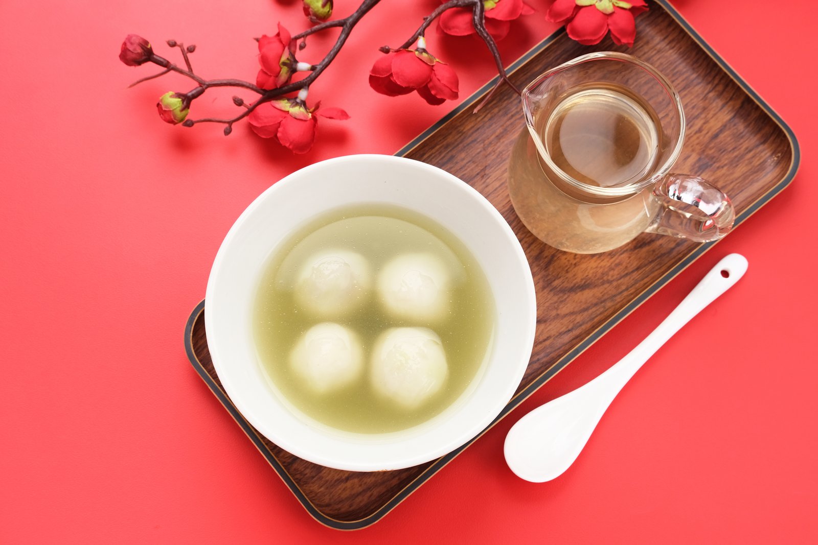 Four white tangyuan floating in clear syrup in a bowl